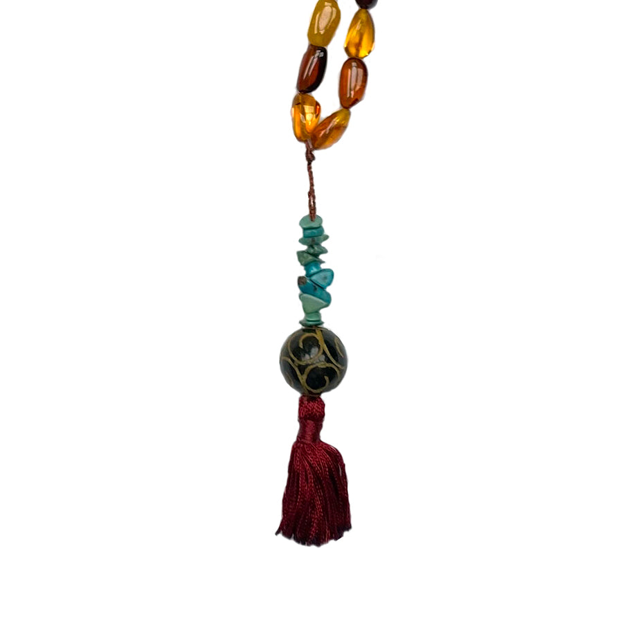Turquoise and Chinese Jade with dark red short tassel of a tibetan mala necklace on white background