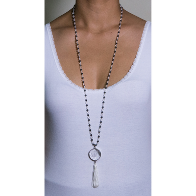 mala necklace with 162 beads of 4 mm of crystal clear quartz, 4 mm of hematite with Eyes of Horus carved crystal clear quartz set in silver 925 and white tassel on model in white top