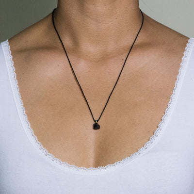 black garnet pendant on black artificial string short necklace with silver 925 clasp on model in white top