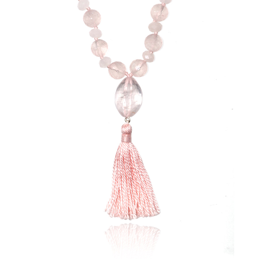 rose quartz pendant and pink tassel of a mala necklace on white background