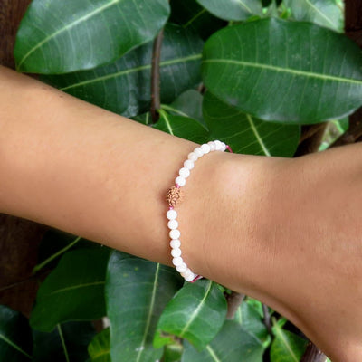 string bracelet with 4 mm pink opal and rudraksha bead centerpiece on horizontal wrist