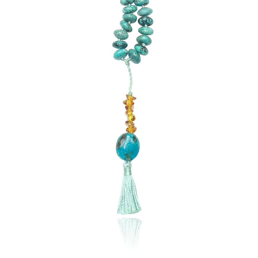 turquoise and amber pendant mala necklace with light blue tassle of a mala necklace on white background