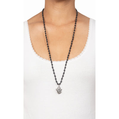 long necklace with hematite and frosted onyx beads with ganesh pendant on model in white top