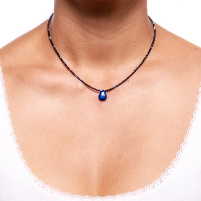 short necklace with 2 mm clue coated black spinel beads and lapis lazuli pendant with silver 925 chain extender on model in white top