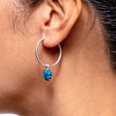 one of a pair of silver earrings with floral carved Cavansite on left ear of a model