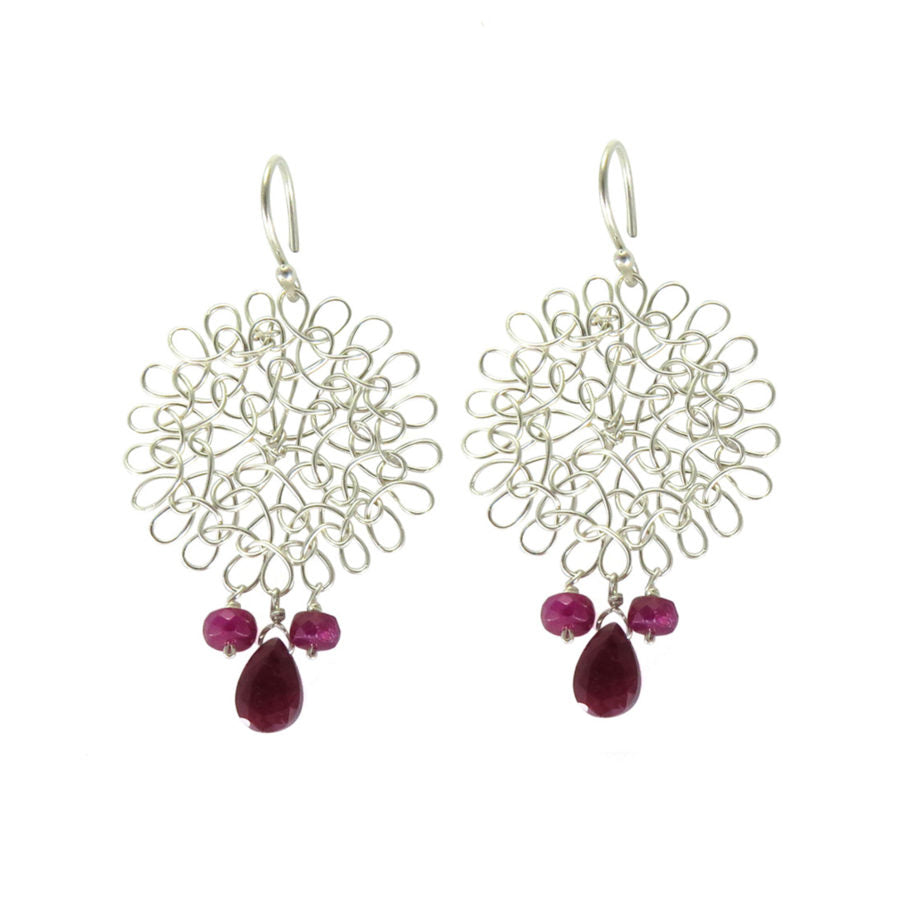 a pair of silver earrings with ruby drops on white background